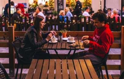A couple having a dinner together while seated outside of a restaurant.