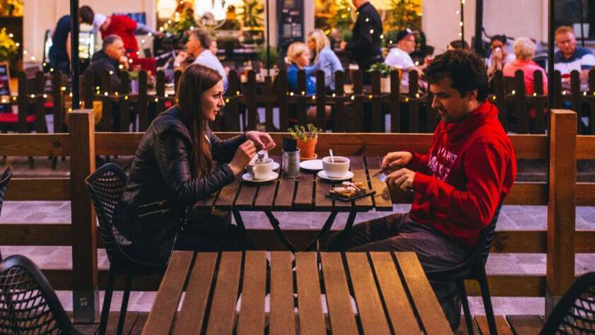 A couple having a dinner together while seated outside of a restaurant.