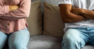 An image of a couple in an argument while sitting on a couch.