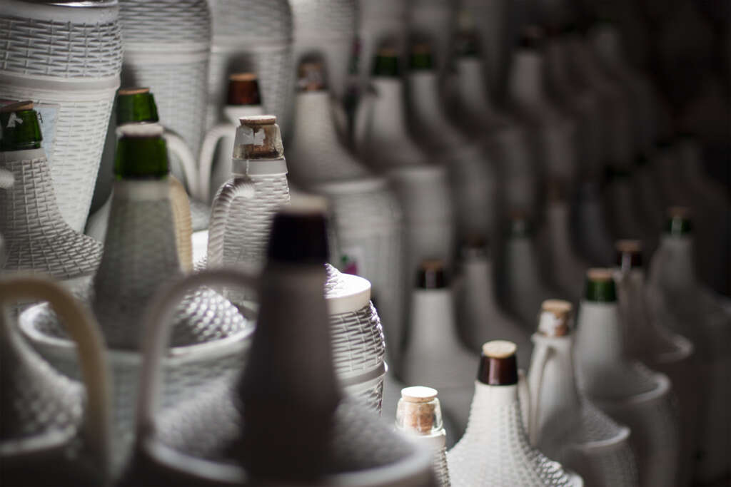 Bottles of wine that have been lined up in a dark-lit cellar. 