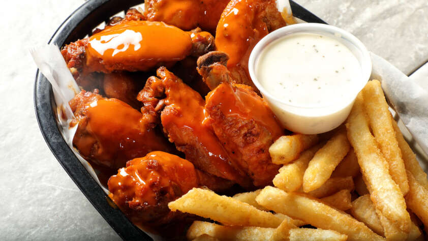 An image of wings and fries in a basket.