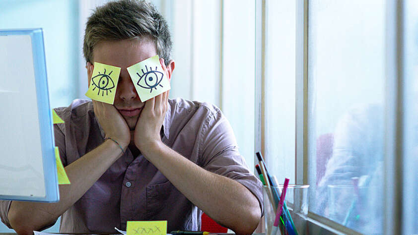 An image of a young employee with sticky notes on his face.