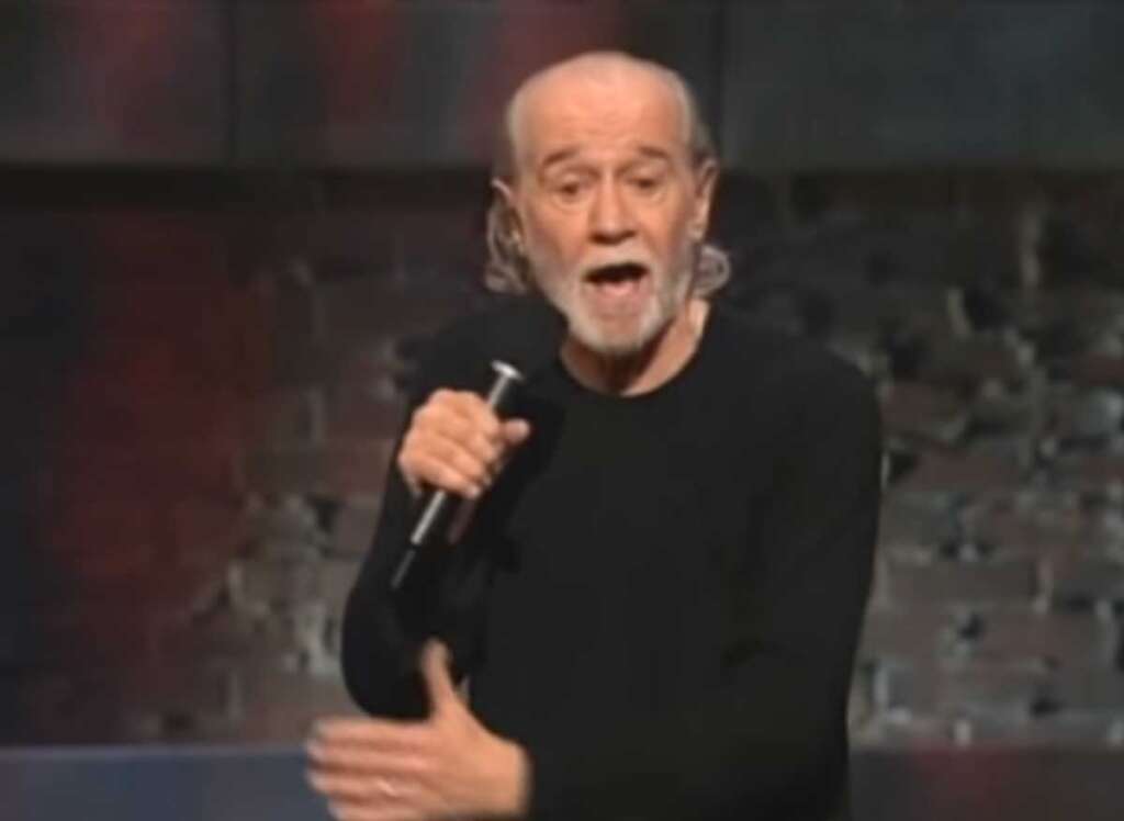George carlin in a black sweater doing standup