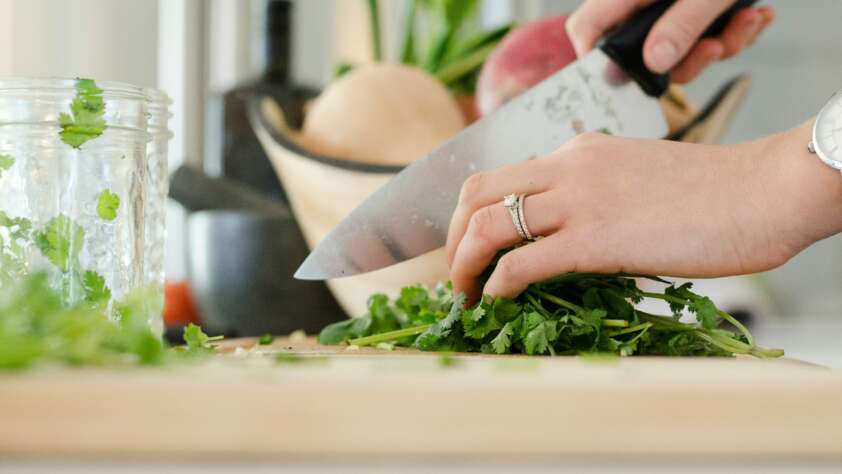 An image of someone cutting herbs with a chef's knife.