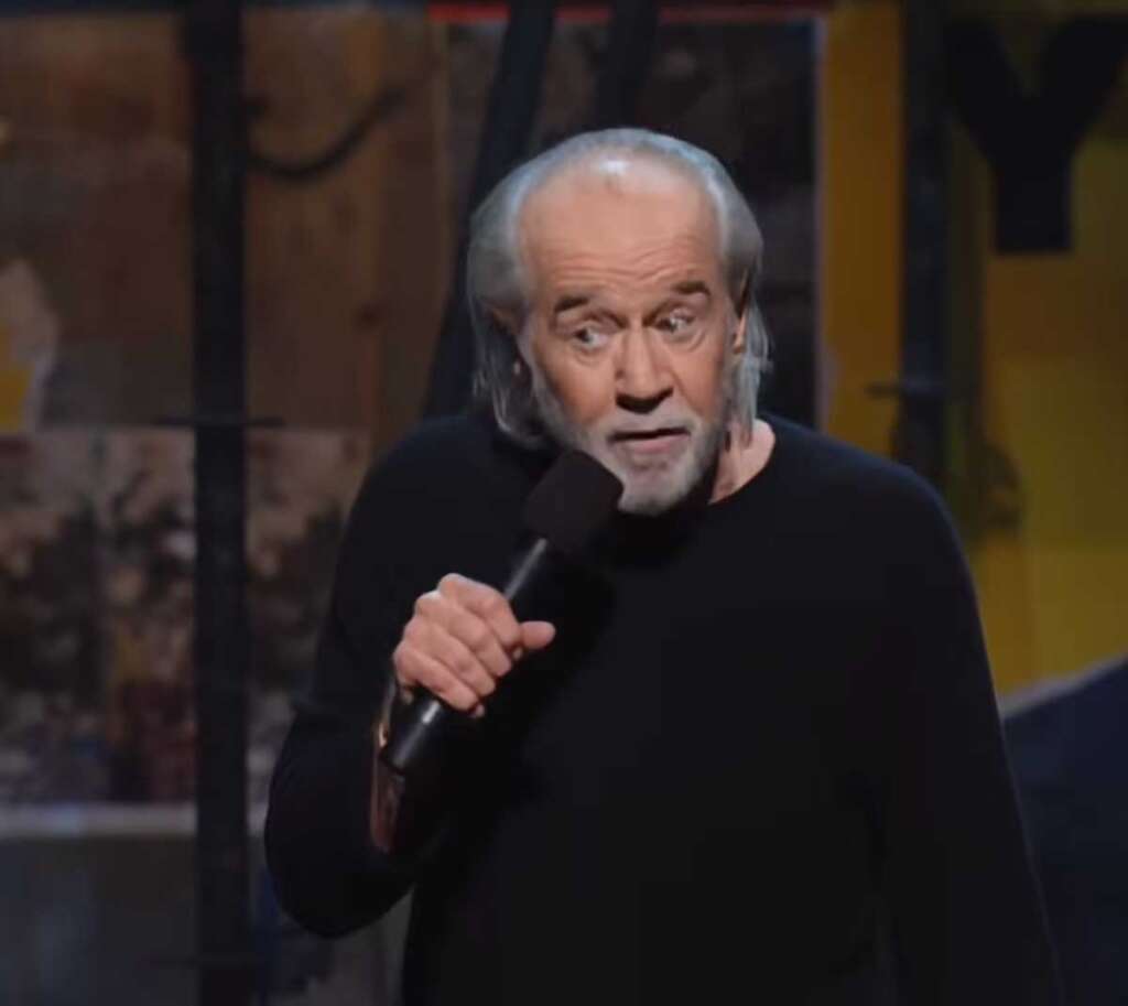 George Carlin looking sideways at the audience while doing standup in 2001