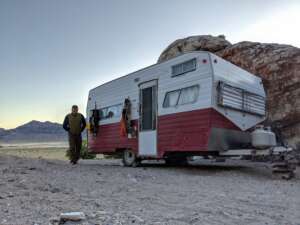 An image of a man walking away from his RV when parked in the desert.