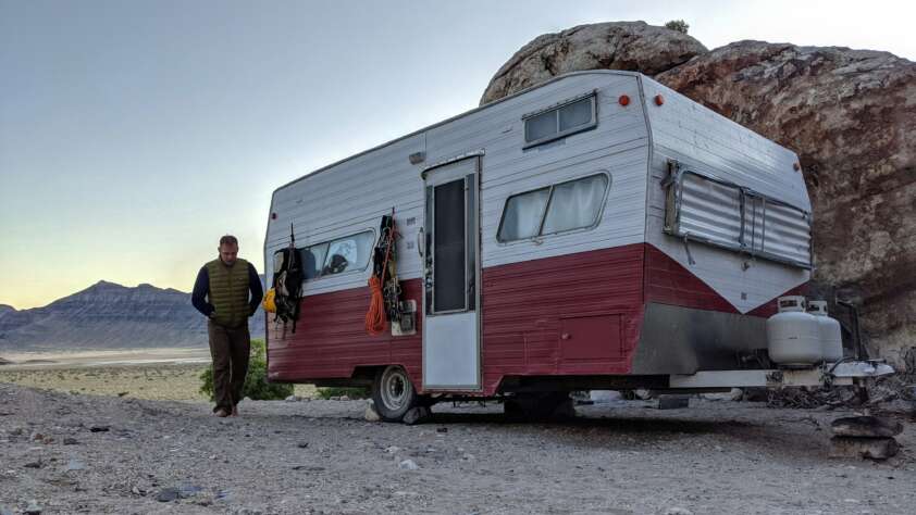 An image of a man walking away from his RV when parked in the desert.