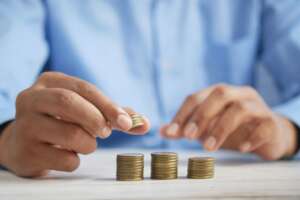 An image of a person in a blue shirt counting gold-colored coins.