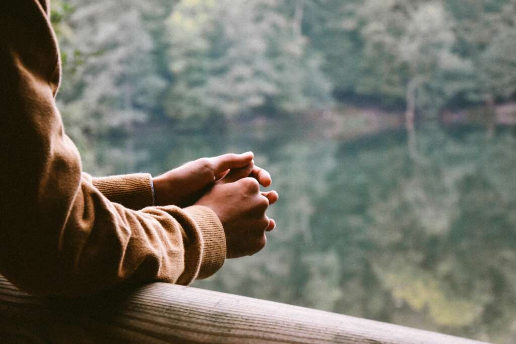 An image of someone looking out the window with their hands crossed. 
