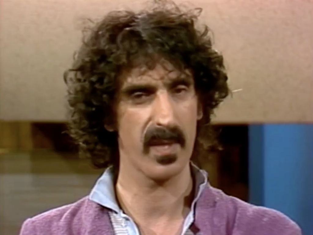 Frank Zappa wearing a purple jacket on an interview