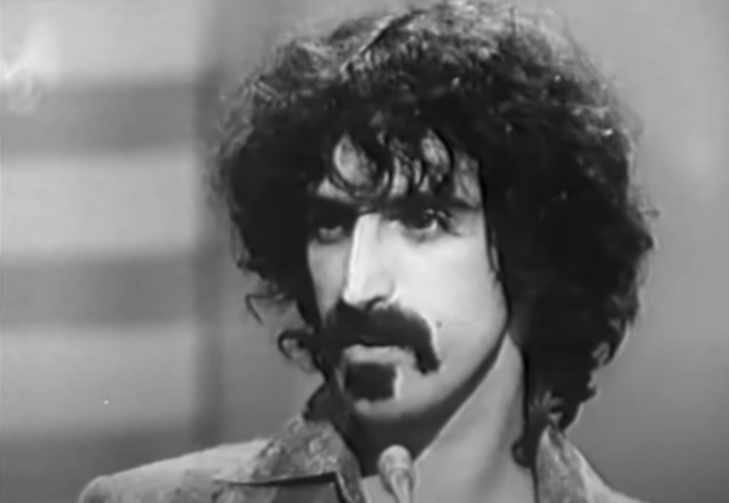 Black and white still of Frank Zappa on tv