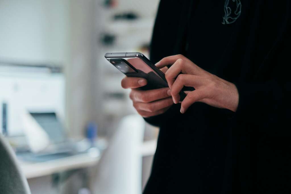 A person in a dark shirt using their smartphone. 