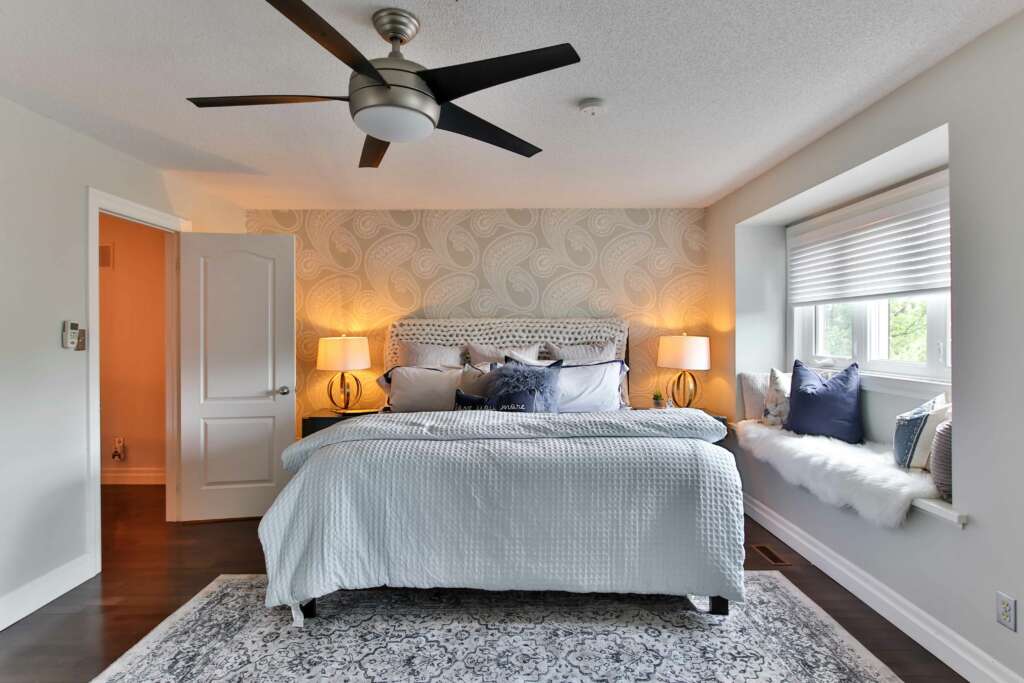 A ceiling fan located over a bed. 