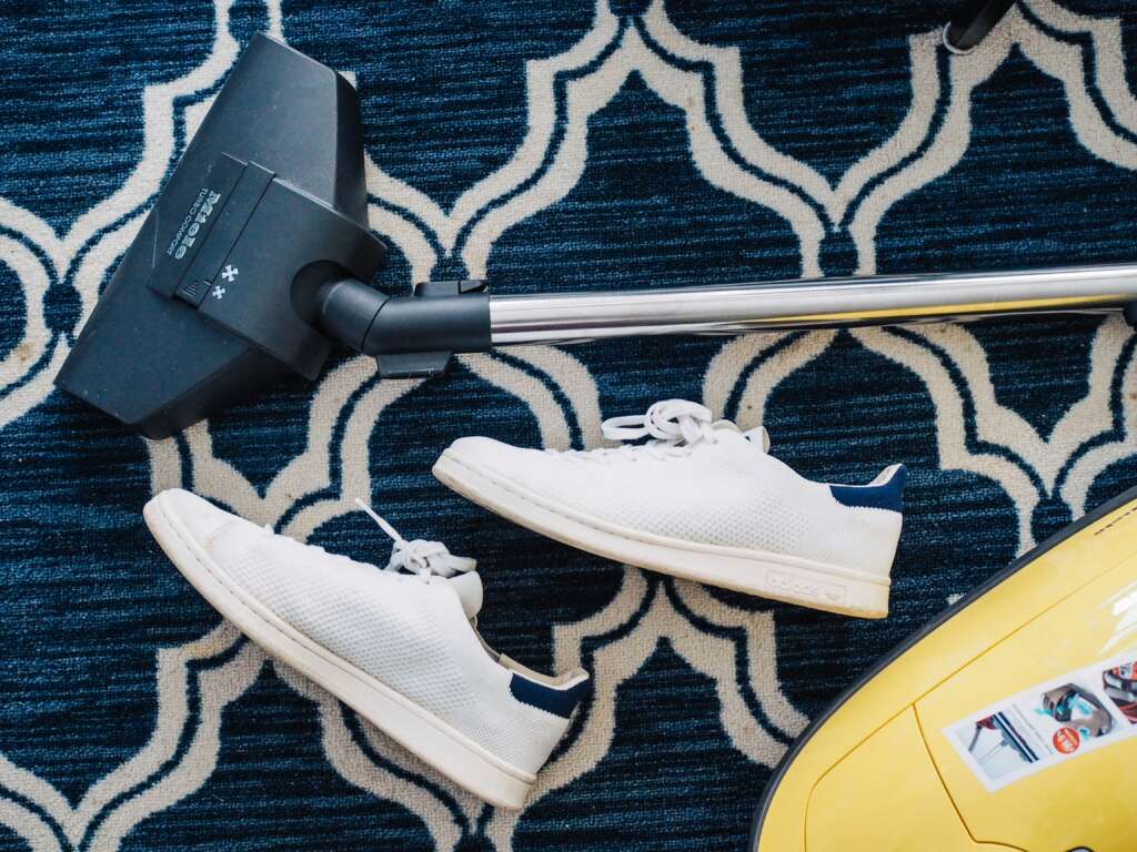 An image of a vacuum cleaner next to a pair of shoes that have been tossed around. 