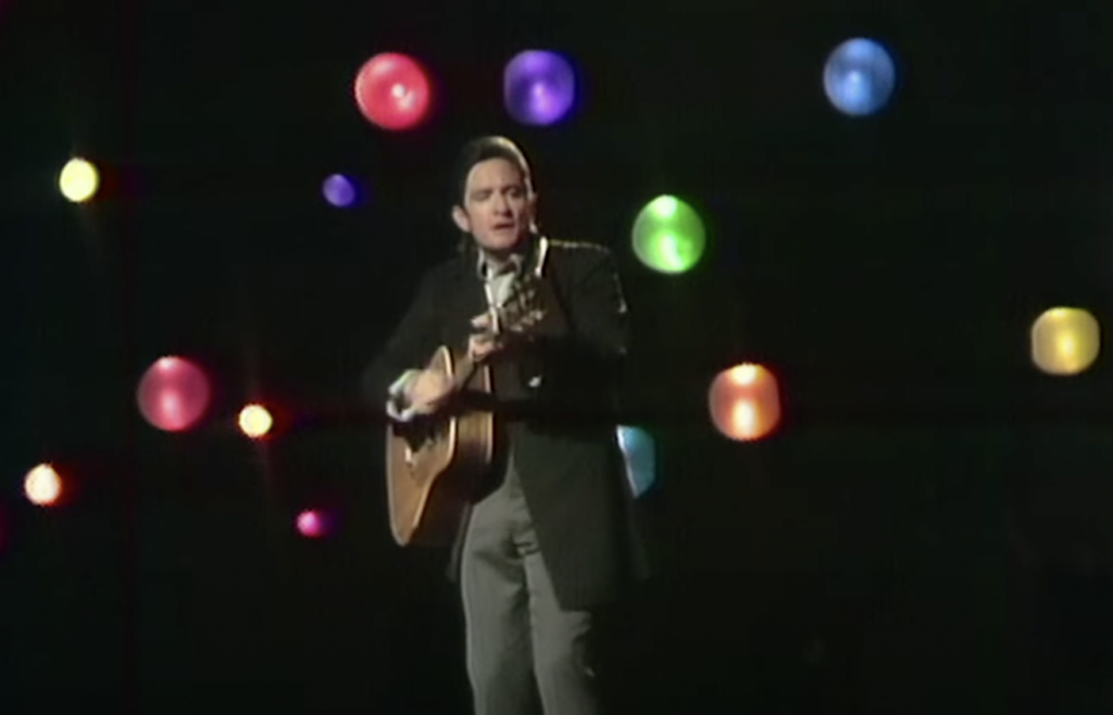 Johnny Cash playing guitar in front of multicolored lights.