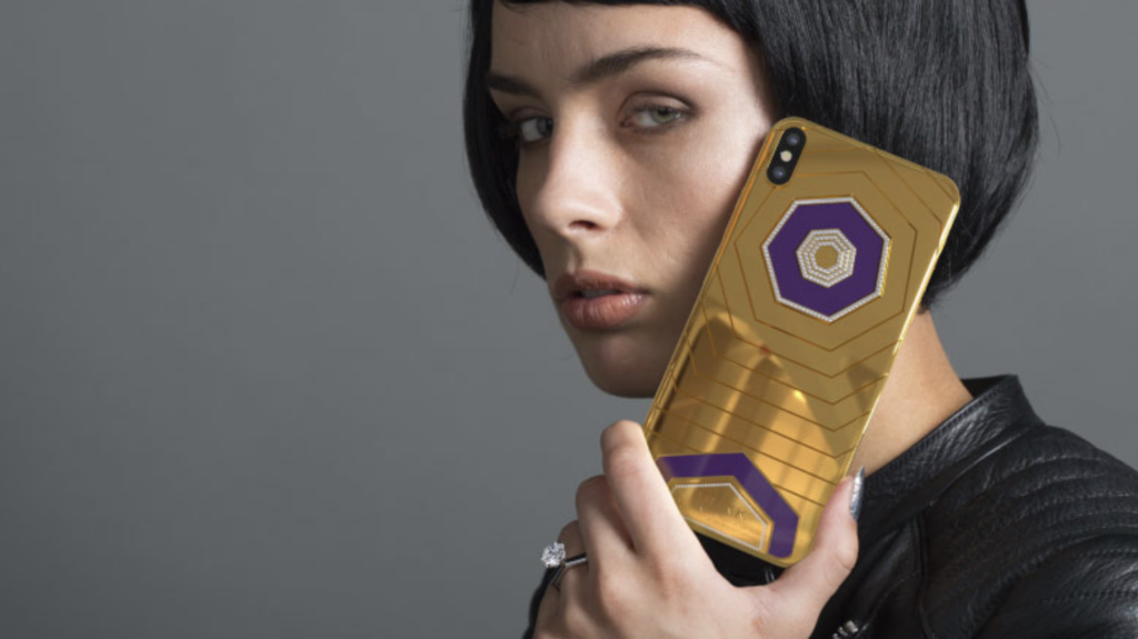 An image of someone holding up a gold Brikk Trim iPhone case. 
