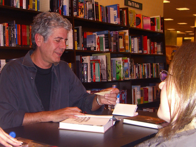 An image of Anthony Bourdain signing a book. 
