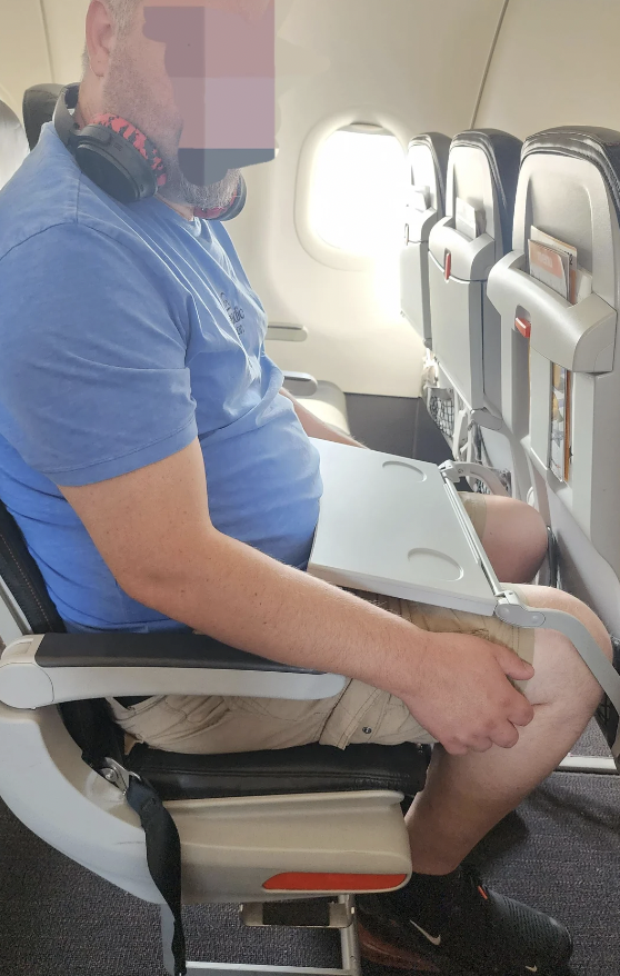 A tall man stuck on a very small flight. 