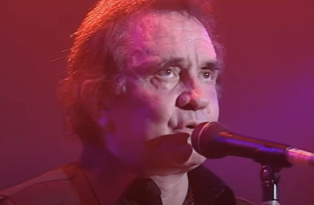 Close-up of an older Johnny Cash singing on stage. 