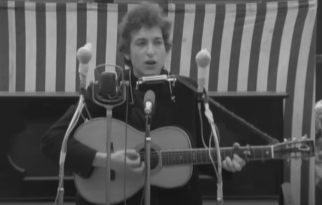 A still image of Bob Dylan in concert. 