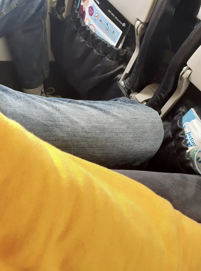 An image of someone shoving their foot onto another flight passenger's armrest. 