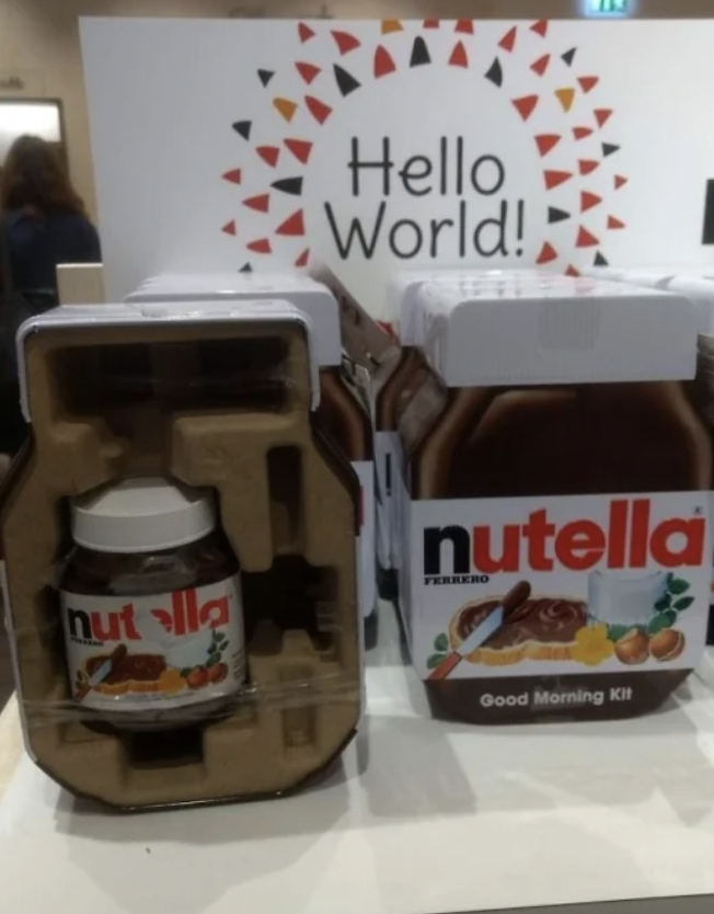A mini Nutella container that's been placed inside of a giant cardboard Nutella box. 