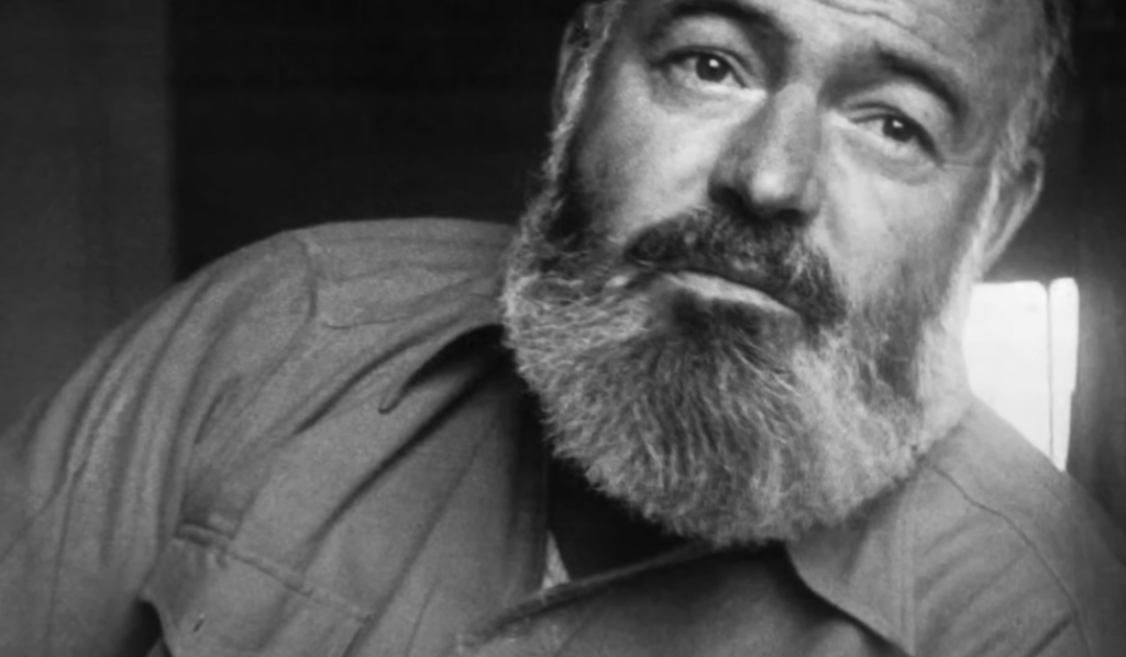 A heavily bearded Ernest Hemingway stares off into the distance. 