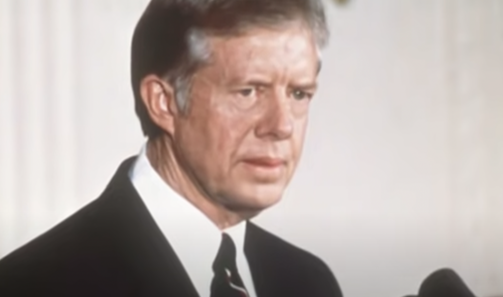 An image of Jimmy Carter talking into the microphone. 