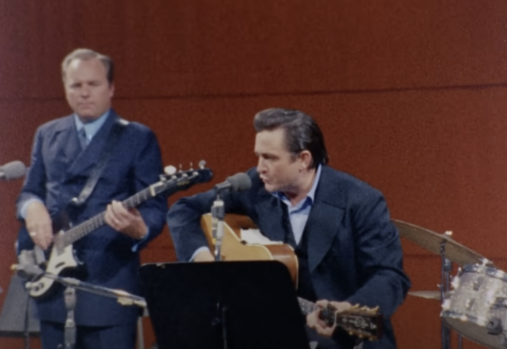 Zoomed out shot of Johnny Cash singing in the studio. 