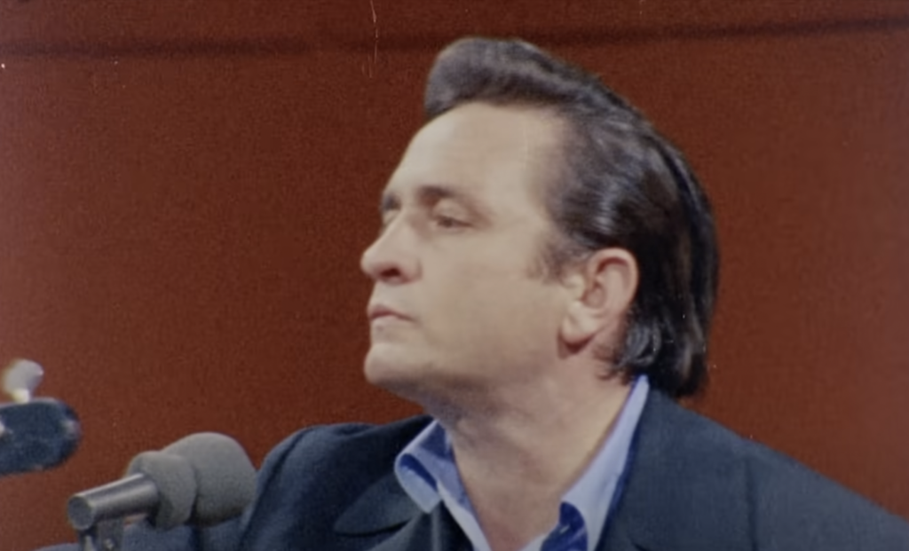 Johnny Cash staring off into the distance and looking serious while in the studio. 