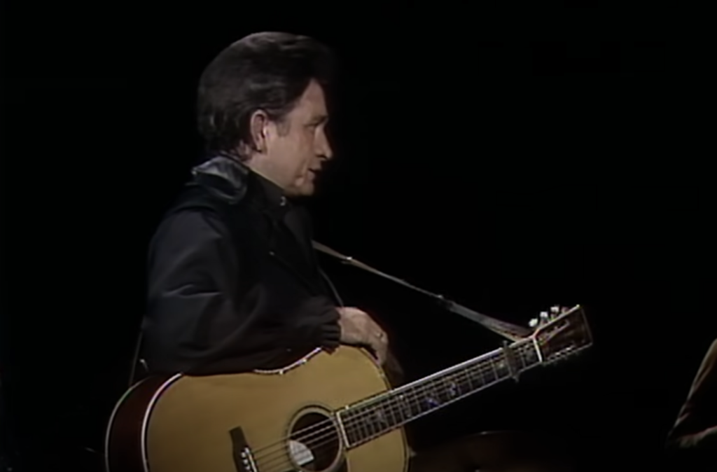 Johnny Cash staring at crowd with guitar. 