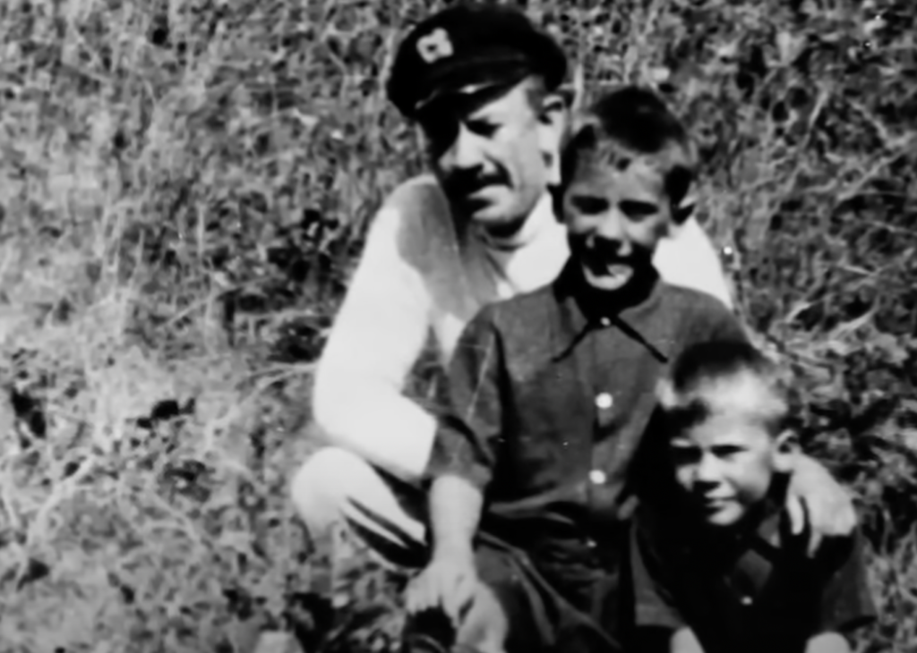 John Steinbeck posing with his kids while wearing sea captain's hat. 
