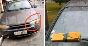 The image shows a car with two unusual features. On the left, one of its headlights is covered with packaging tape. On the right, a squeegee is wedged under the windshield wiper to serve as a replacement.