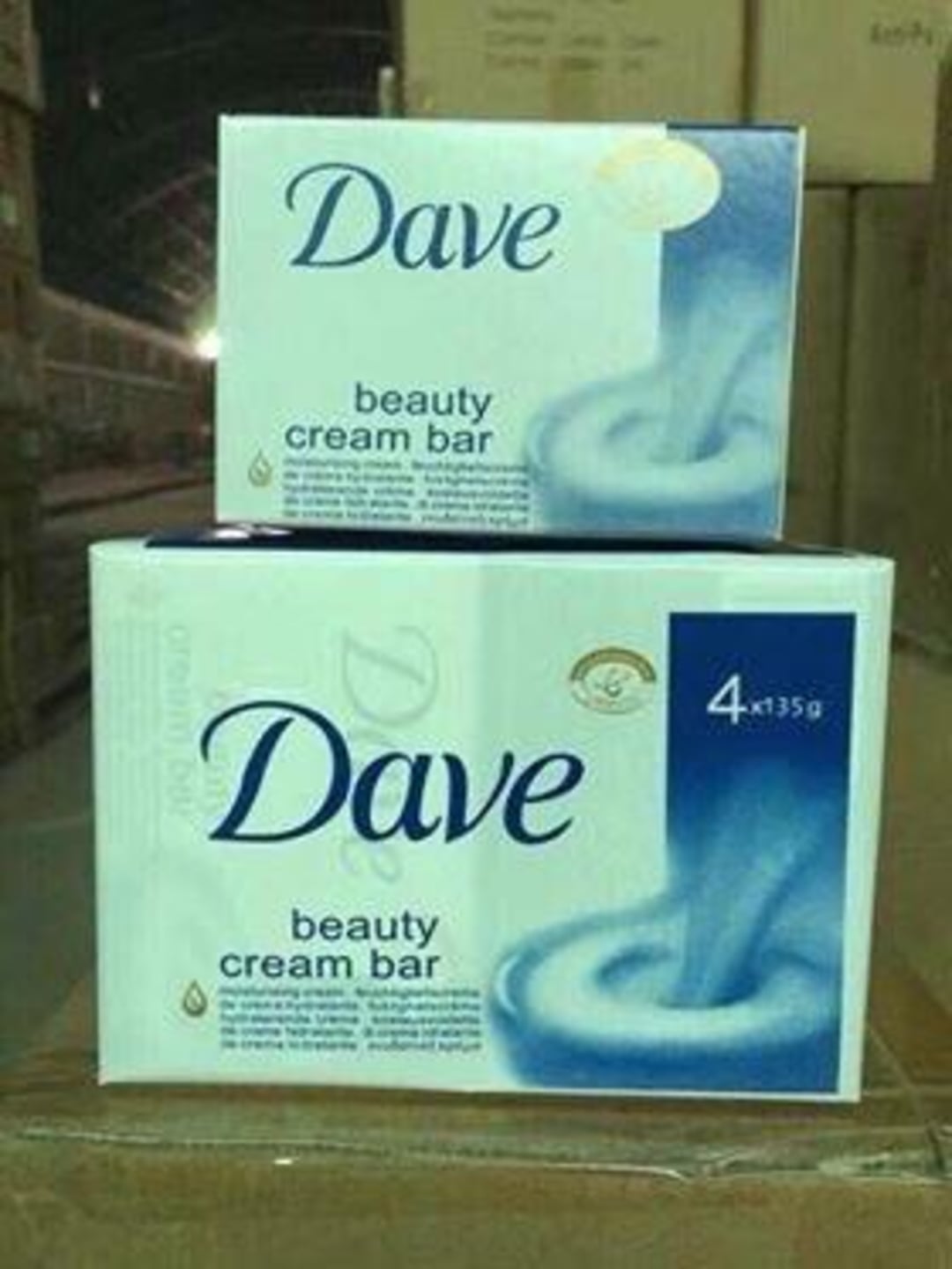 Two boxes of soap labeled "Dave beauty cream bar" are stacked on a cardboard box. The packaging has a blue and white swirl design and contains four bars each.