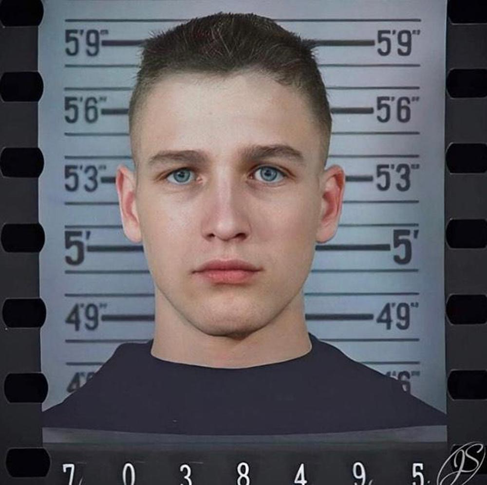 A young man is facing the camera against a height chart, which measures up to approximately 5'9". He has short hair and a serious expression. The background suggests this is a mugshot or identification image.