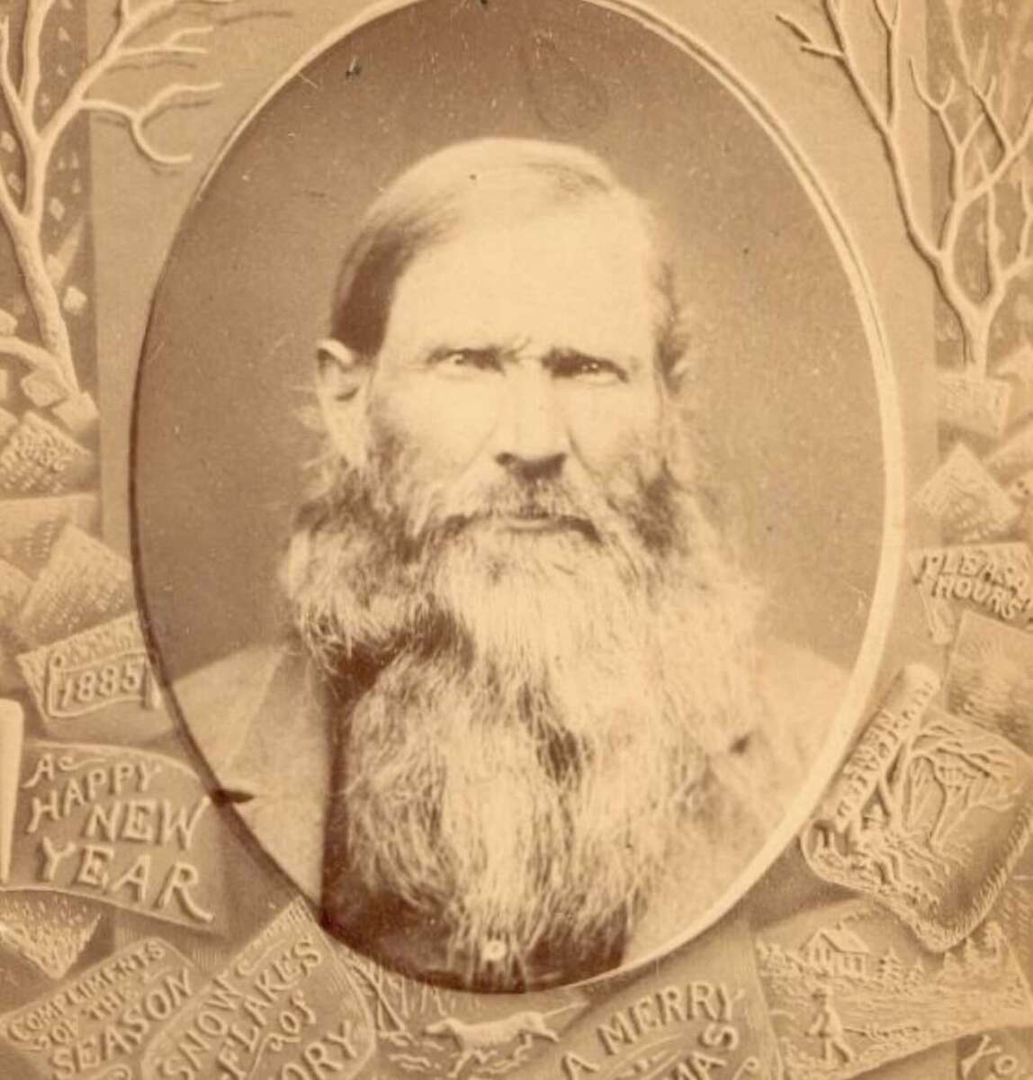 Sepia-toned portrait of an older man with a long beard and serious expression, surrounded by ornate New Year and holiday-themed decorations and inscriptions, including “1885,” “A Happy New Year,” and “A Merry Christmas.”
