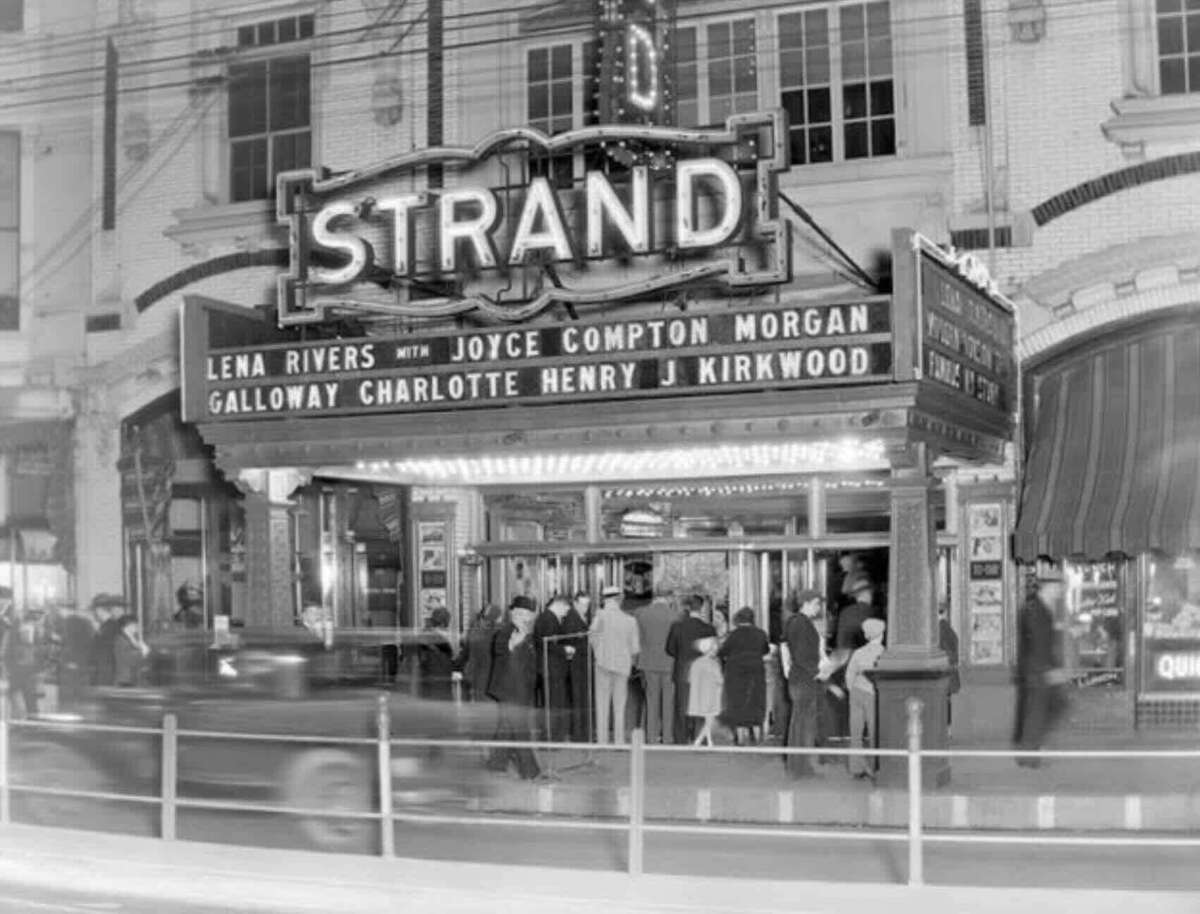 Black-and-white photo of people gathered under a lit marquee for the Strand Theater, advertising “Lena Rivers” with Joyce Compton, Morgan Galloway, Charlotte Henry, and J. Kirkwood. Vintage cars are blurred in front.