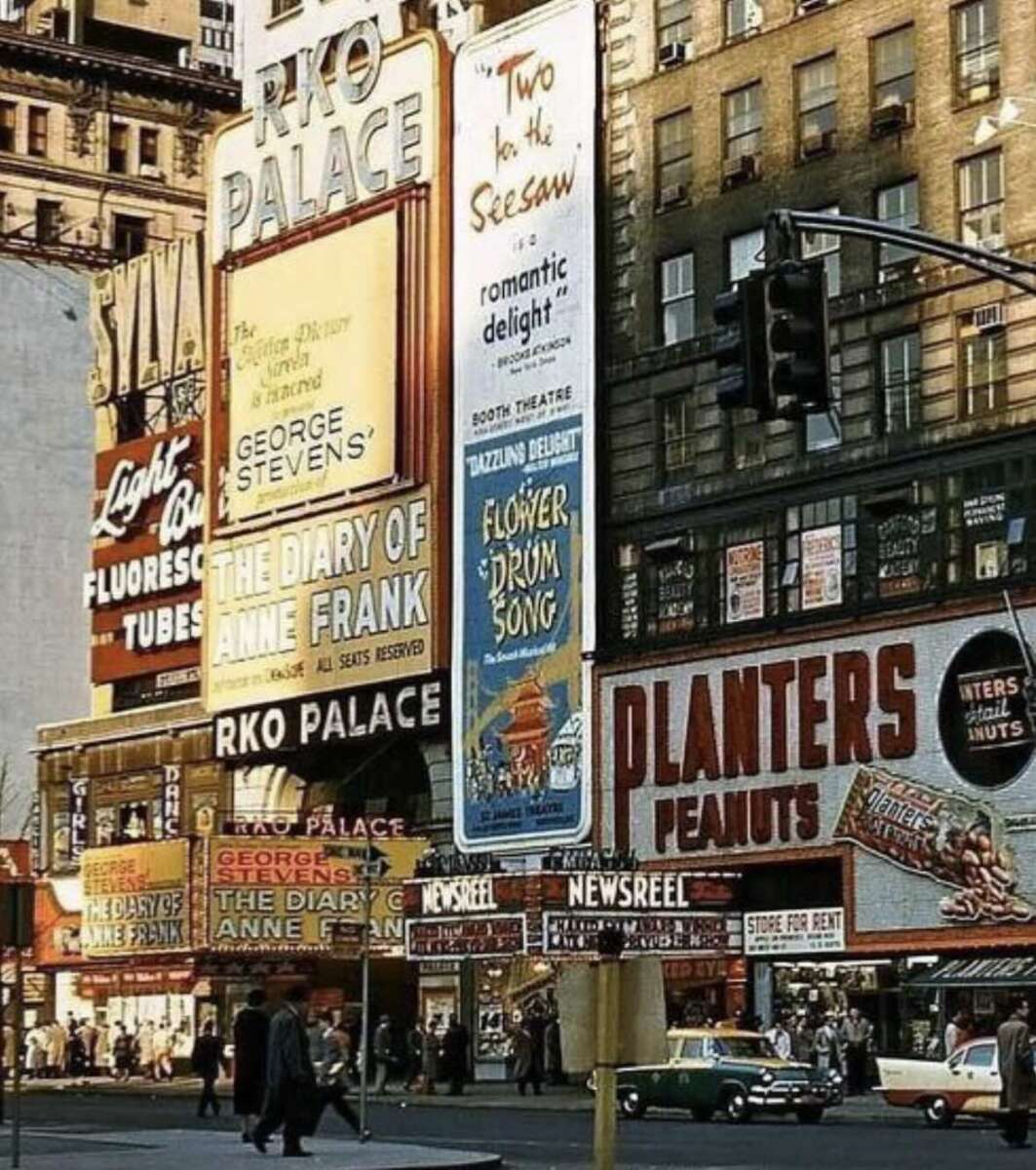 Vintage photo of a busy city street with people walking, cars parked, and large theater billboards advertising shows like "The Diary of Anne Frank," "Flower Drum Song," and "Two for the Seesaw.