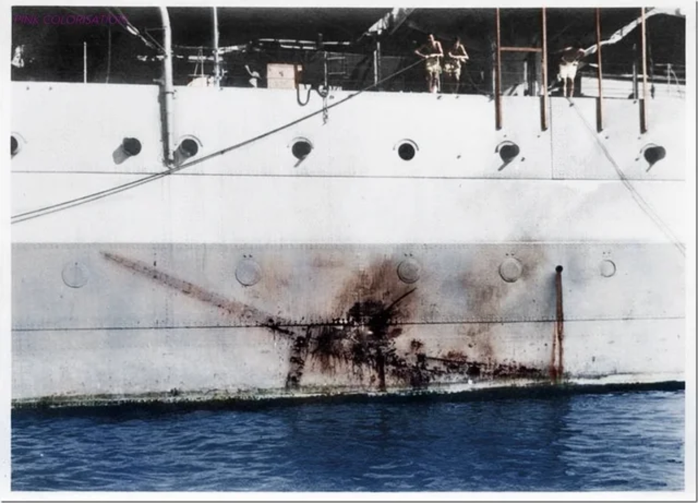 A colorized photo of a ship’s hull shows a large, dark impact mark and rust below several portholes above the waterline, with two people standing on the deck above.