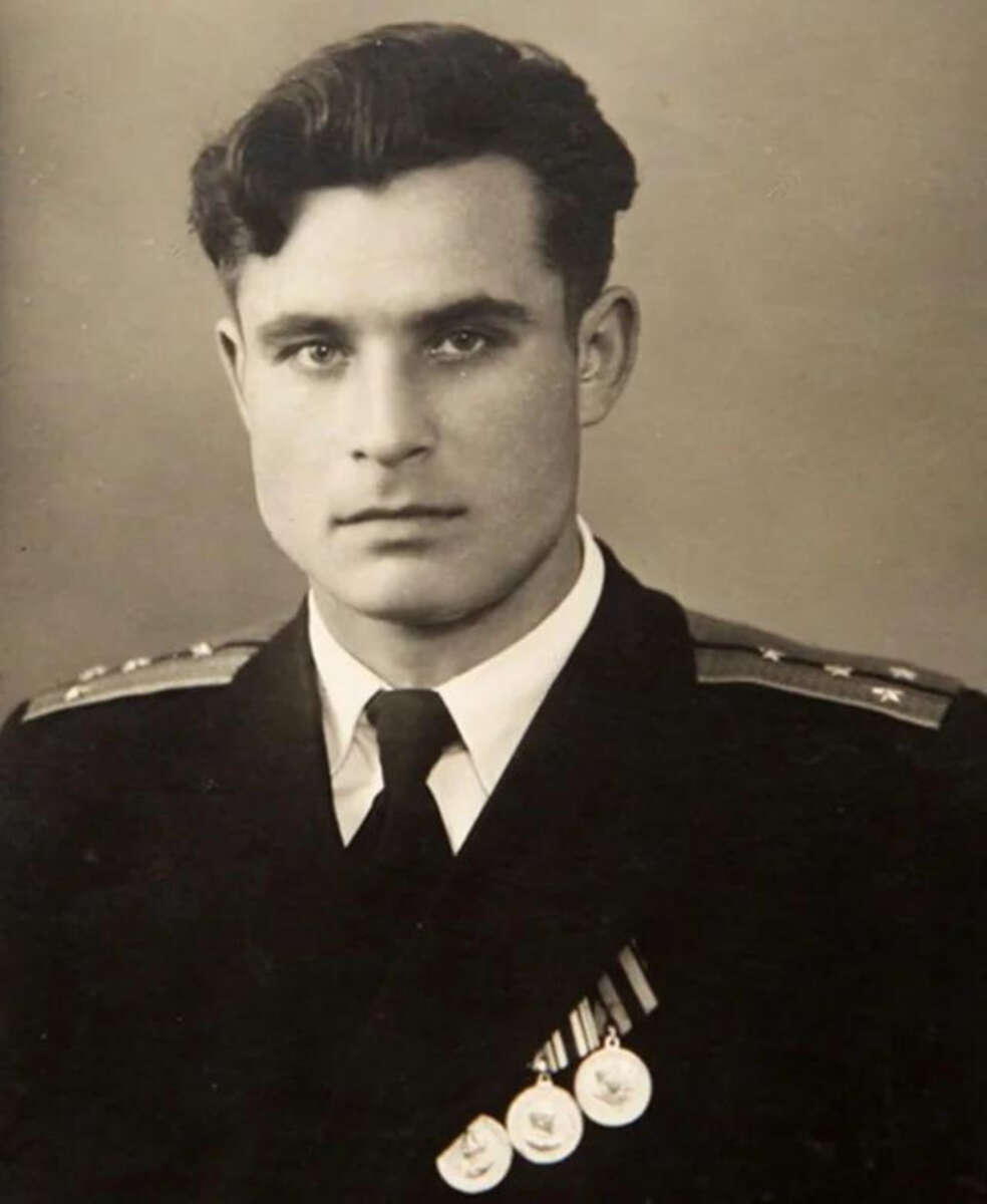 A young man in a military uniform with shoulder epaulettes and three medals on his chest poses for a formal black and white portrait. He has short, dark hair and a serious expression.