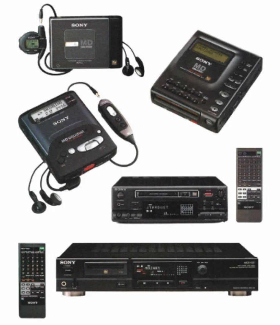 A collection of vintage Sony audio equipment, including portable MiniDisc players, headphones, remote controls, and two larger stereo components with matching remotes, all shown against a white background.