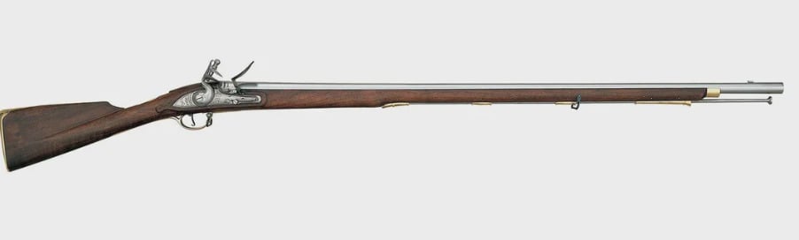 A long-barreled, antique flintlock musket with a wooden stock, metal trigger guard, and fittings, displayed on a plain, light background.