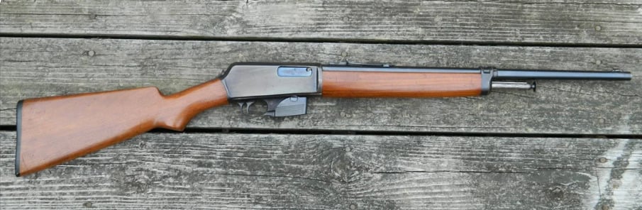 A lever-action rifle with a wooden stock and forearm, and a metal barrel and receiver, lying on weathered wooden planks.