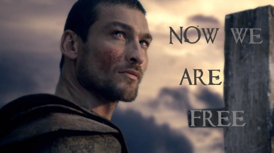 A man with a determined expression and slight facial injuries looks into the distance against a dramatic sky. Beside him, bold text reads, "NOW WE ARE FREE.
