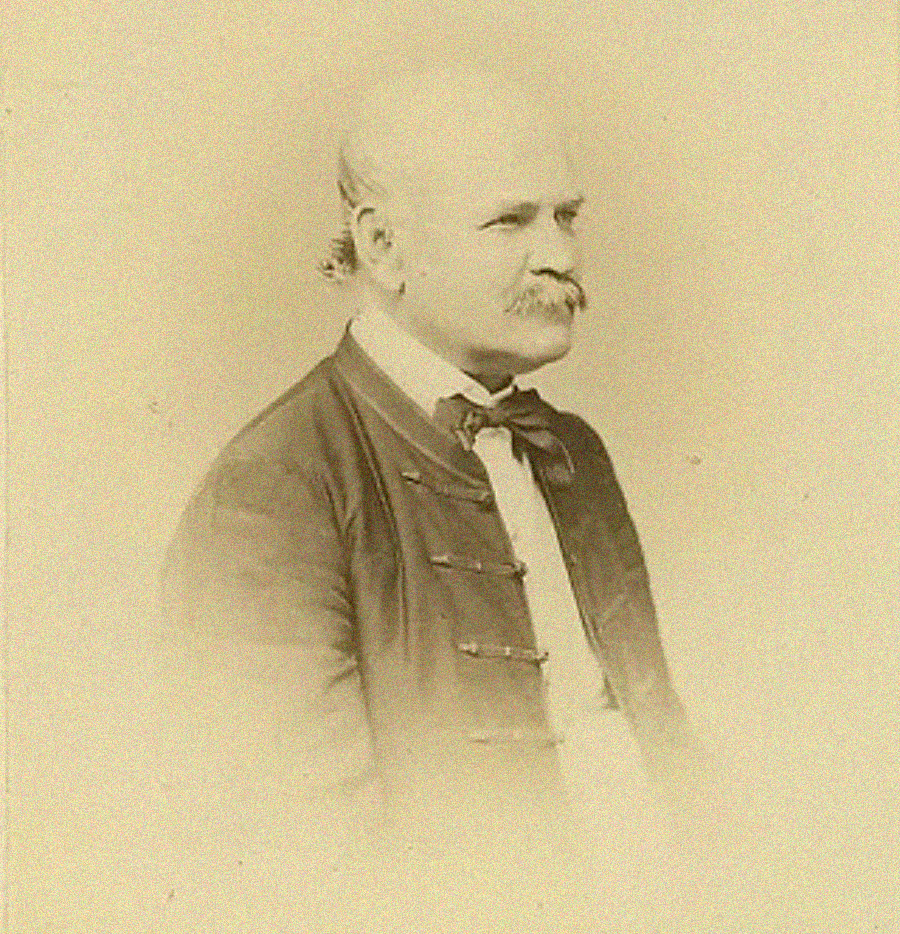 Sepia-toned portrait of an older man with a mustache, wearing a bow tie and formal jacket, facing to the right against a plain background.