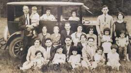 Black and white photo of a family in front of a car in the 1930s