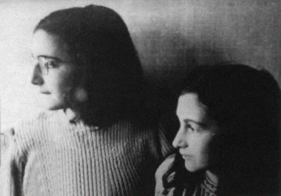 Two young women with dark hair sit close together, looking thoughtfully in opposite directions. The image is in black and white, creating a soft, contemplative atmosphere.