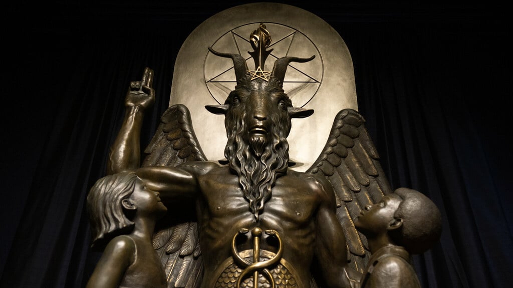 Statues of Baphomet and 2 children looking at him.