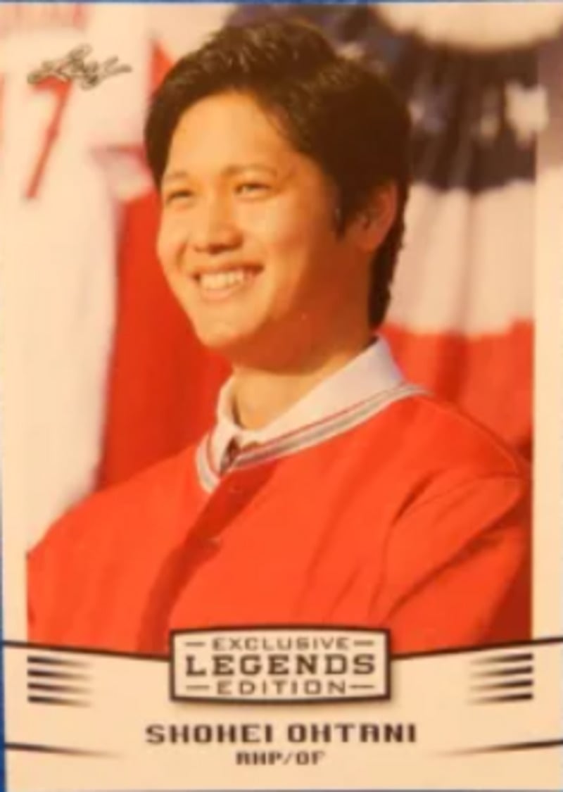 A baseball card featuring a smiling man in a red jacket, standing in front of an American flag backdrop. The card reads "Exclusive Legends Edition" and "SHOHEI OHTANI RHP/OF" at the bottom.