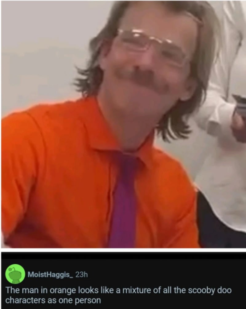 A man with glasses, a mustache, and long hair wears an orange shirt and purple tie, smiling. A comment below says he looks like a mixture of all the Scooby-Doo characters as one person.